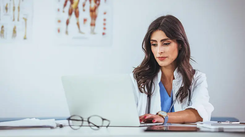 Image of a Dr at her desk looking at her computer