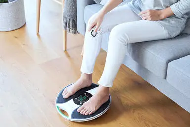 Close up image of lady with her feed on the device and holding the remote