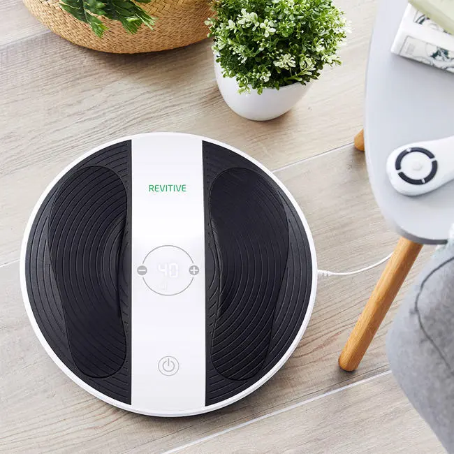 Image of the prohealth device, in a home setting, with wooden flooring bottom on chair and plant
